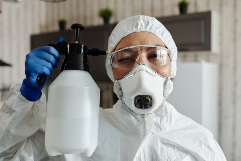 Técnico de controle de pragas aplicando produto saneante em ambiente residencial usando equipamento de proteção individual