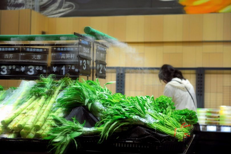 Técnico em equipamento de proteção aplicando controle de pragas em corredor de supermercado